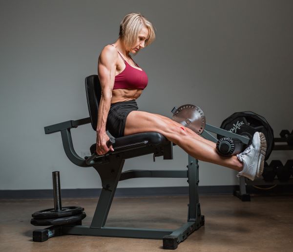 woman using rotary leg curl machine